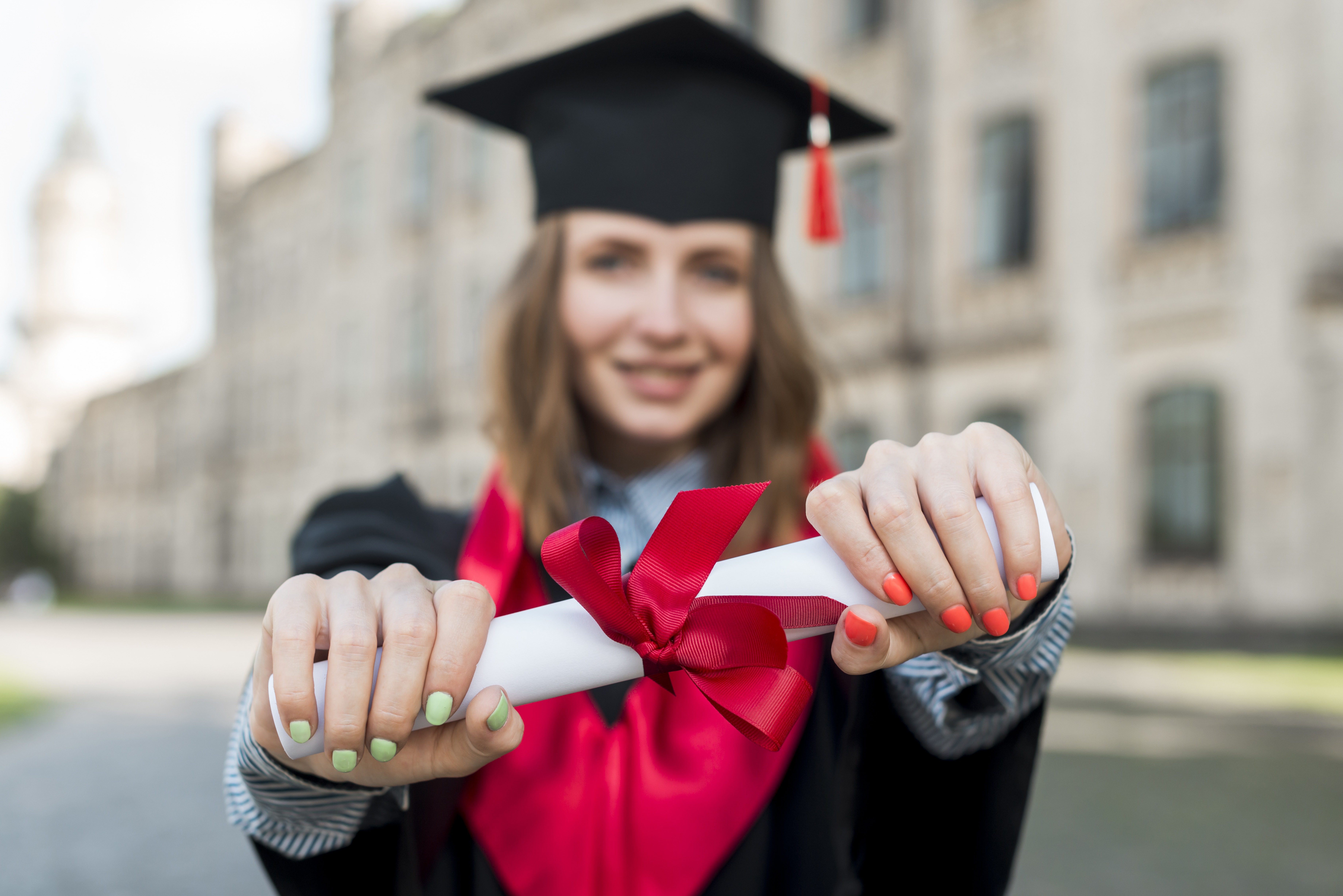 Graduate holding a rolled diploma with two hands out front